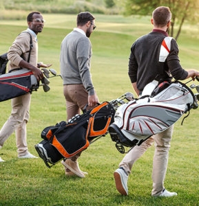 Three male golfers walking across a golf course
