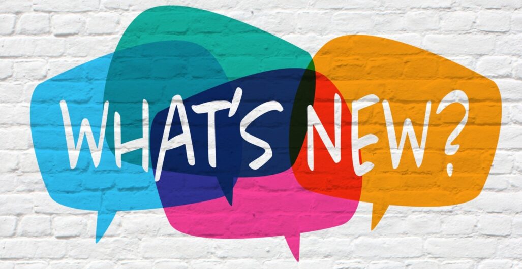 A white brick wall with four colorful speech bubbles and the words “WHAT’S NEW?” in white.