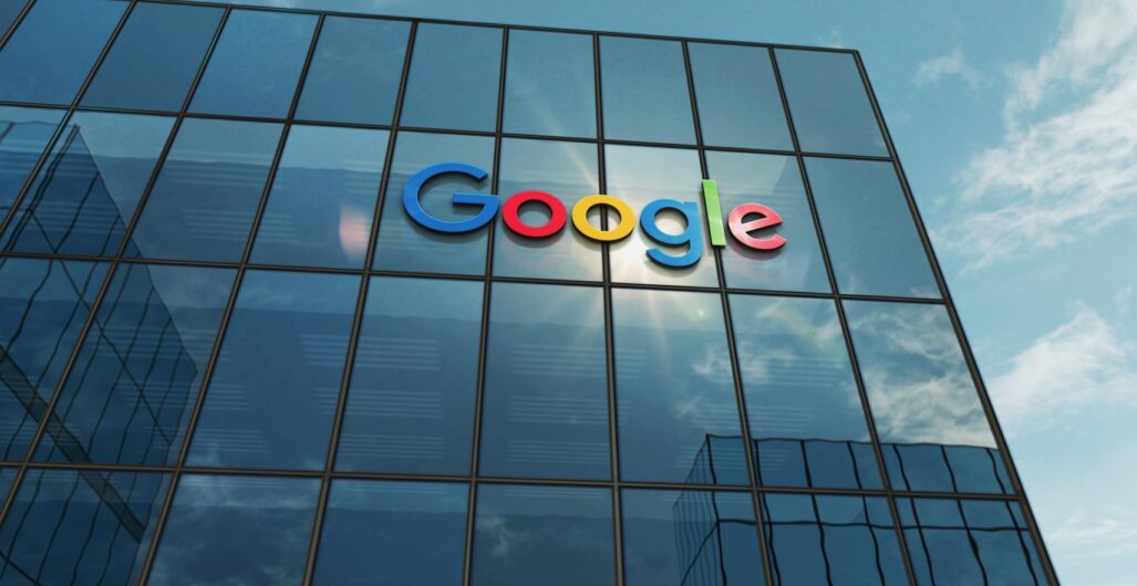 Office Building with Tall Windows, the Google Logo on Four of the Windows, and a Blue Sky with Clouds Behind It