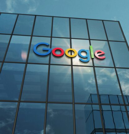Office Building with Tall Windows, the Google Logo on Four of the Windows, and a Blue Sky with Clouds Behind It