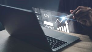 Online programmatic ad on a laptop display screen with a hand holding a stylus tracing the increase in results. 