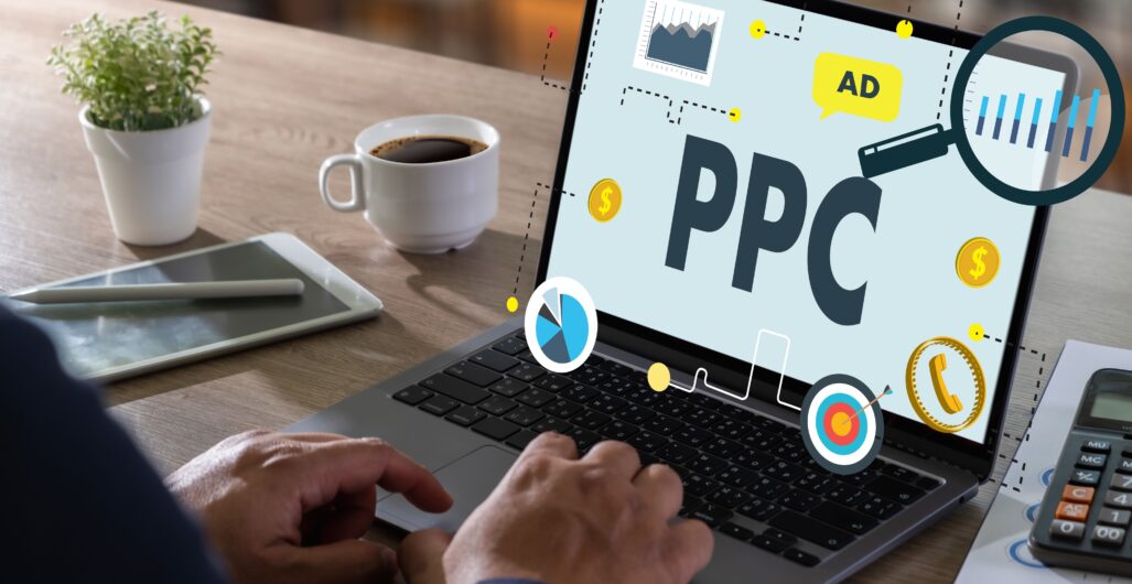 A man’s hands hover over a laptop keyword with digital graphics and the word ”PPC” floating off of the laptop screen